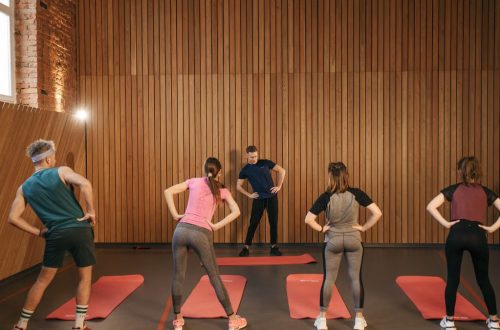 People stretching on yoga mats during a fitness class indoors.